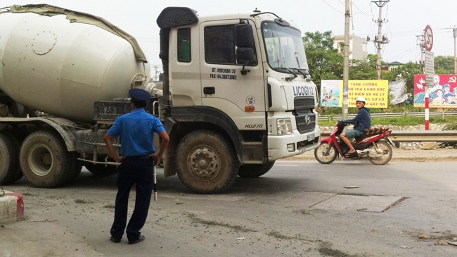 Thanh tra giao thông chống nạnh đứng trên bê tông rơi nhìn xe bồn vi phạm, trước mặt là biển báo cấm xe tải vào phố Kim Giang. Ảnh: A.T