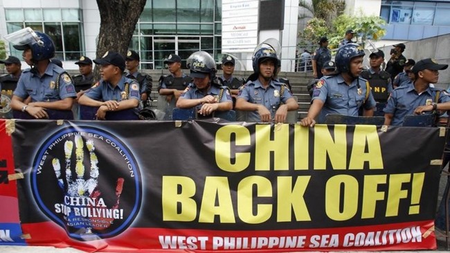 Cảnh sát Philippines đứng trước banner của người dân nước này phản đối Trung Quốc gây hấn trên biển Đông. Ảnh: Philstar