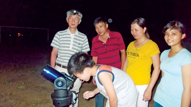 Thầy Fumitaka (ngoài cùng) hướng dẫn trẻ em và người dân Hội An quan sát bầu trời qua kính thiên văn. Ảnh: Nguyễn Trang
