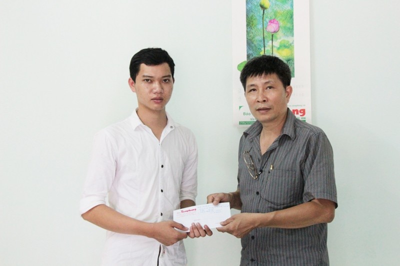 Nhà báo Trần Tuấn - Trưởng VP đại diện miền Trung (báo Tiền Phong) trao quà của bạn đọc giúp đỡ em Nguyễn Văn Sỹ (bên trái).