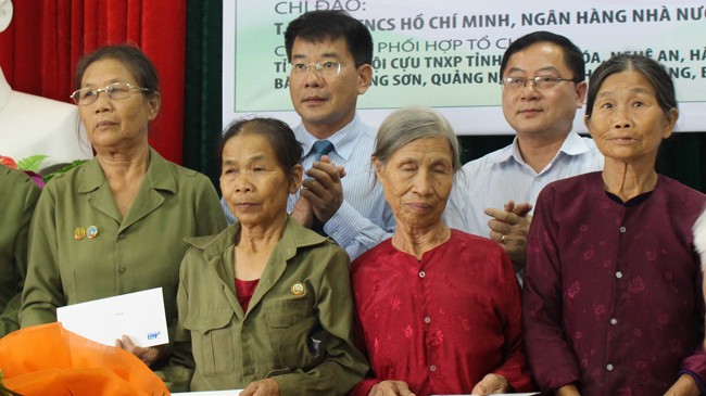 Ông Vũ Trần Thái - Giám đốc chi nhánh MB Thanh Hóa (hàng sau bên trái) và nhà báo Lê Xuân Sơn trao quà và chụp ảnh lưu niệm với cựu TNXP. Ảnh: Hoàng Lam