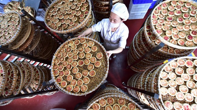 Nhân viên nhà máy bánh kẹo Yiting bên những chiếc bánh Trung thu đang đợi nguội. Ảnh: Xinhua