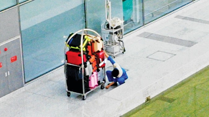 Lương thấp, hợp đồng bấp bênh là tác nhân khiến công nhân bốc xếp hành lý tại sân bay phải tìm cách “kiếm thêm”? Ảnh: L.H.V. Trong ảnh: Nhân viên bốc xếp săm soi hành lý...