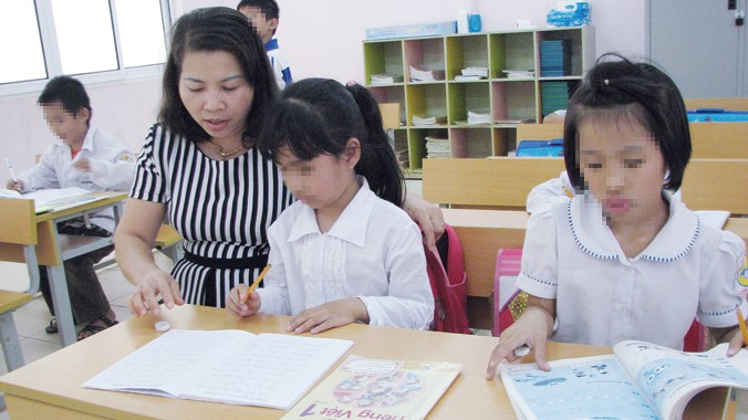 Cô giáo Thủy cầm tay nắn nót từng nét chữ cho trẻ có H ở Trung tâm giáo dục lao động xã hội số II, Ba Vì, Hà Nội.