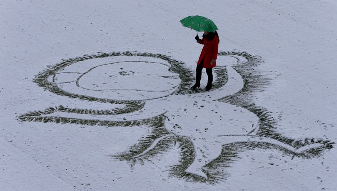 Một giáo viên vẽ hình con khỉ trên sân trường phủ đầy tuyết ở tỉnh Giang Tô. Ảnh: Xinhua
