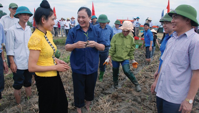 Bí thư Tỉnh ủy Yên Bái Phạm Duy Cường (người cầm cây ngô non) và Giám đốc sở Nông Nghiệp Trần Thế Hùng (bên phải) xuống ruộng với nhà nông.