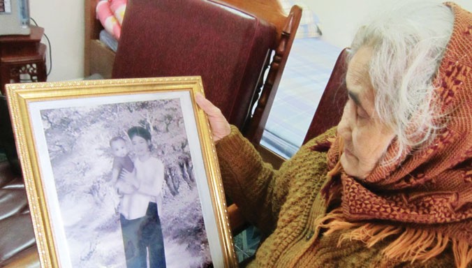 Cụ Khương Thị Chu- mẹ liệt sĩ Lê Đình Chinh- với bức ảnh kỷ niệm Chinh hồi nhỏ. Ảnh: Hoàng Lam