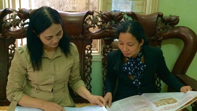 Chị Nguyệt và chị Phạm Thị Oanh (bên phải - người đấu tranh chống tiêu cực cùng chị Nguyệt) xem lại những bài báo viết về vụ việc. Ảnh: T.Hà