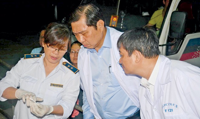 Kiểm dịch viên Nguyễn Thị Bích Nguyệt (bìa trái) đang chỉ cho ông Huỳnh Đức Thơ, kết quả test nhanh kiểm tra chất tạo nạc.