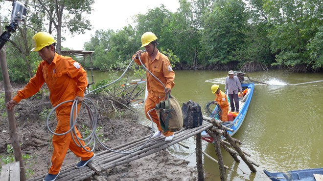 Thợ điện vùng sông nước Cà Mau triển khai kéo điện về cho dân. Ảnh: Đình Hoàng