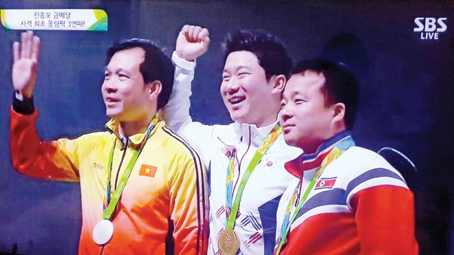 Xạ thủ Hoàng Xuân Vinh (bìa trái) trên bục nhận huy chương. Ảnh: Đình Thoa