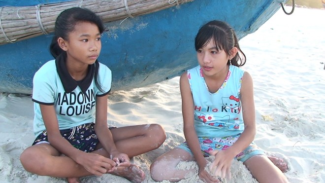 Hai cháu Thơm và Hòa ngồi ngóng cha ngoài biển để vơi đi nổi nhớ mẹ đang làm thuê ở miền Nam.