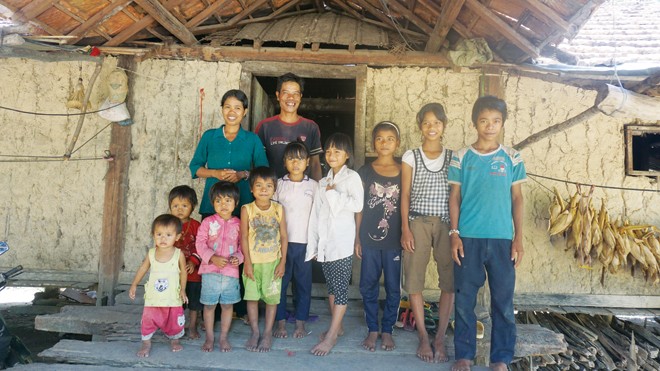 Vợ chồng A Thai-Y Đ’ưi và 9 đứa con (một đứa được gửi ở nhà ông bà ngoại) trước căn nhà rộng nhưng trống trơn. Ảnh: L.A