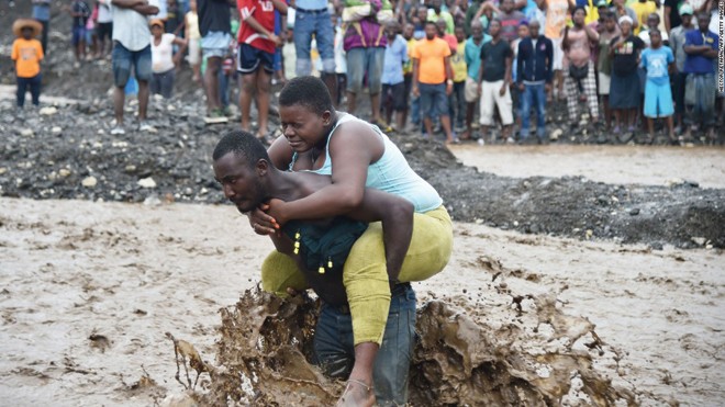 Người dân Haiti cõng nhau vượt sông vì cầu sập trong bão Matthew. Ảnh: Getty Images
