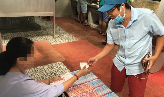 PV Tiền Phong mua vé số điện toán tại một điểm bán dạo ở trạm dừng chân tại Vĩnh Long. Ảnh: Lê Nguyễn
