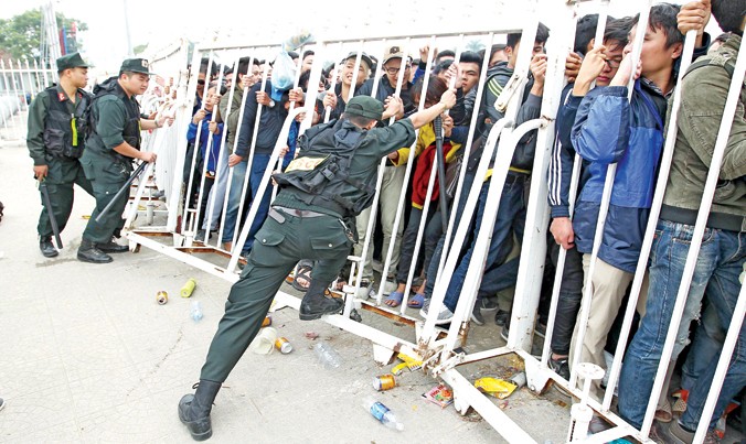 Lực lượng an ninh vất vả chống giữ hàng rào trước sức “tấn công” của người hâm mộ. Ảnh: Như Ý