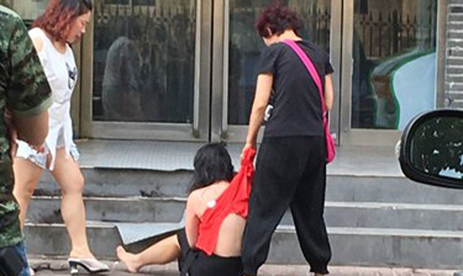 Một phụ nữ bị cáo buộc ngoại tình bị lột áo, bị đánh đập trên đường phố Trịnh Châu, tỉnh Hà Nam ngày 12/7. Ảnh: CFP