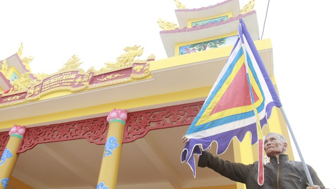 Ông Nguyễn Đăng Thiện (87 tuổi, tộc Nguyễn Đăng) treo lá cờ trước ngôi nhà thờ vừa được sơn mới của dòng họ Nguyễn Đăng. Ảnh :Thanh Trần