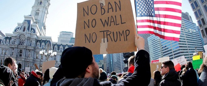Một người biểu tình ở Mỹ hôm qua giơ tấm biển ghi “Không lệnh cấm (nhập cảnh), Không tường (dọc biên giới Mỹ-Mexico), Không Trump”. Ảnh: ABC News