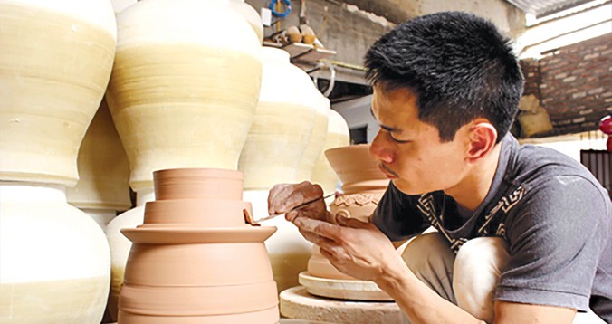 Anh Phạm Anh Đạo đang hoàn thiện sản phẩm gốm của mình. Ảnh: Q.L