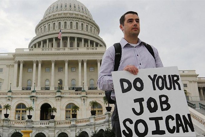 Một nhân viên liên bang Mỹ đứng ngoài tòa nhà Quốc hội giơ tấm biển có dòng chữ: “Hãy làm việc của các ông để tôi có thể làm việc của tôi”, sau khi chính phủ Mỹ bị đóng cửa tạm thời. Ảnh: Larry Downing.