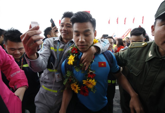 Cầu thủ Vũ Văn Thanh bị người hâm mộ vít cổ chụp tự sướng khi vừa từ thang máy bay xuống tại sân bay Nội Bài. Ảnh: Hồng Vĩnh.
