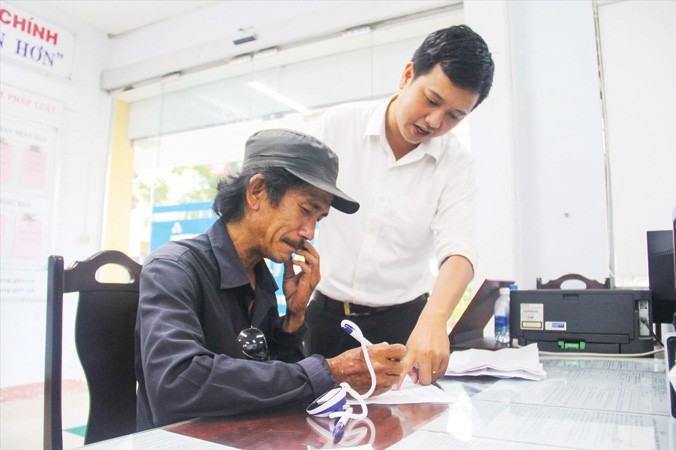 Một người dân được các bạn trẻ ở quận Thanh Khê hướng dẫn cách kê khai thông tin vào mẫu đơn. Ảnh: Thanh Trần. 