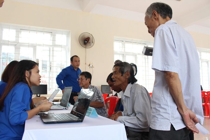 Các TNV hỗ trợ người dân đăng ký tài khoản công dân điện tử và hướng dẫn thực hiện các dịch vụ công trực tuyến trên máy tính. Ảnh: Giang Thanh.