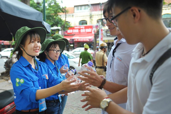 Các tình nguyện viên tại điểm trường THPT Việt Đức trao nước và kèm theo lời chúc may mắn tới sĩ tử. Ảnh: Xuân Tùng.