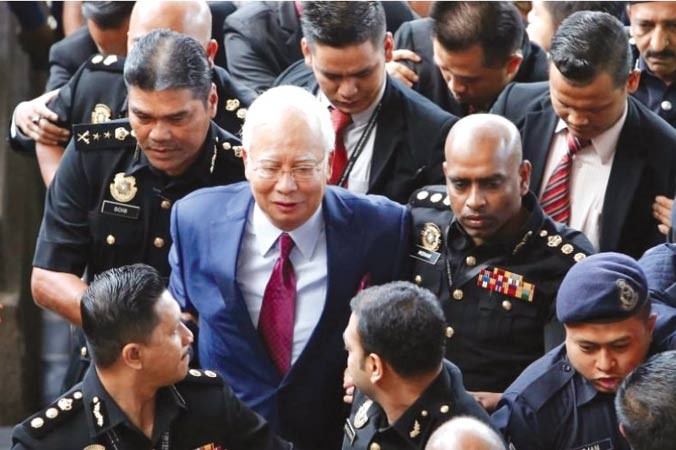 Cựu Thủ tướng Najib Razak rời tòa trước sự bao vây của báo chí. Ảnh: Straits Times.