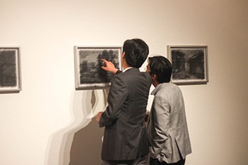 Người xem chăm chú bên một tác phẩm tại triển lãm “In Vitra +”. Ảnh: Ngọc Trâm 