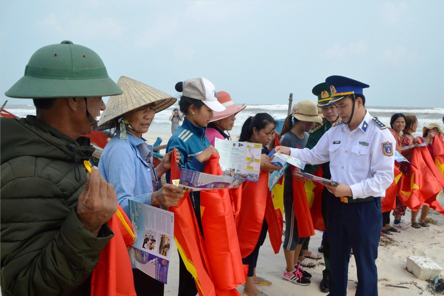 Vùng CSB 1 tặng cờ Tổ quốc và cấp phát tờ rơi tuyên truyền cho bà con ngư dân ở huyện Lệ Thủy (Quảng Bình). Ảnh: M.T
