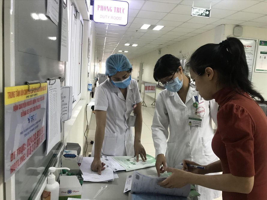 Bác sĩ Ninh (giữa) hướng dẫn người về từ Vũ Hán làm thủ tục y tế. Ảnh: Thái Hà