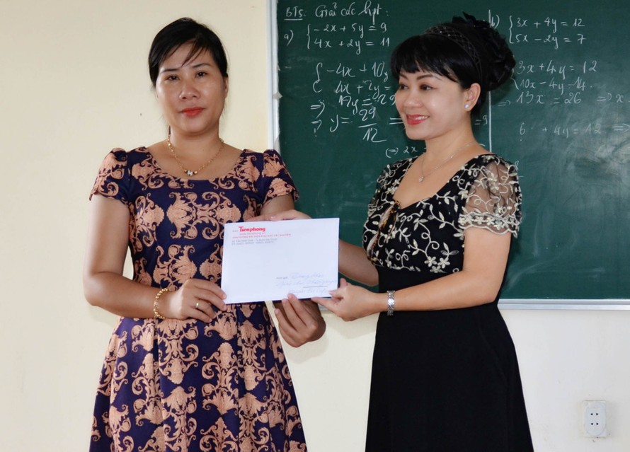 Cô Hồng Phượng (bên trái) nhận tiền hỗ trợ bữa ăn cho trò nghèo từ đại diện báo Tiền Phong