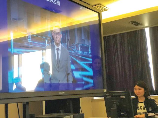 Đại diện Xinhua giới thiệu về người dẫn chương trình tin tức AI (trên màn hình) của hãng tại Bắc Kinh. Ảnh: Thái An 
