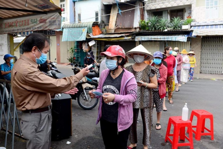 Người dân xếp hàng, đo nhiệt độ khi vào chợ. Ảnh: U.P 