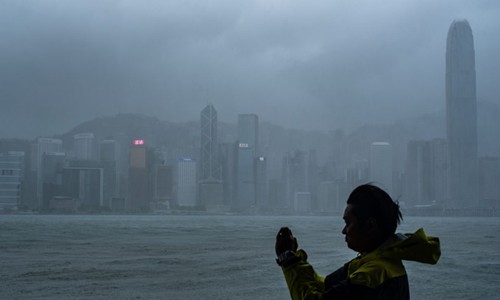 Một người đàn ông cố chụp ảnh ghi lại cảnh bão vào Hong Kong. Ảnh: Asia Times