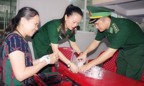 Thượng úy Hà Huy Thiên và đồng đội chia sẻ “Bát cháo tình thương” với người bệnh Ảnh: N.M