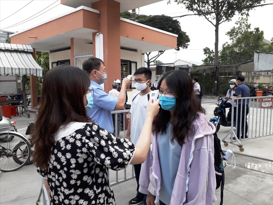Giáo viên trường THPT chuyên Nguyễn Hữu Huân (quận Thủ Đức, TPHCM) đo thân nhiệt cho học sinh khi dịch COVID-19 tái xuất hiện trong cộng đồng. Ảnh: Huy Thịnh 