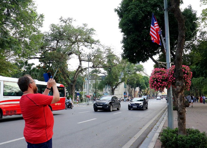 Du khách nước ngoài đứng trên đường Đinh Tiên Hoàng chụp ảnh quốc kỳ Việt Nam-Mỹ-Triều Tiên chiều ngày 21/2. ảnh: Như Ý