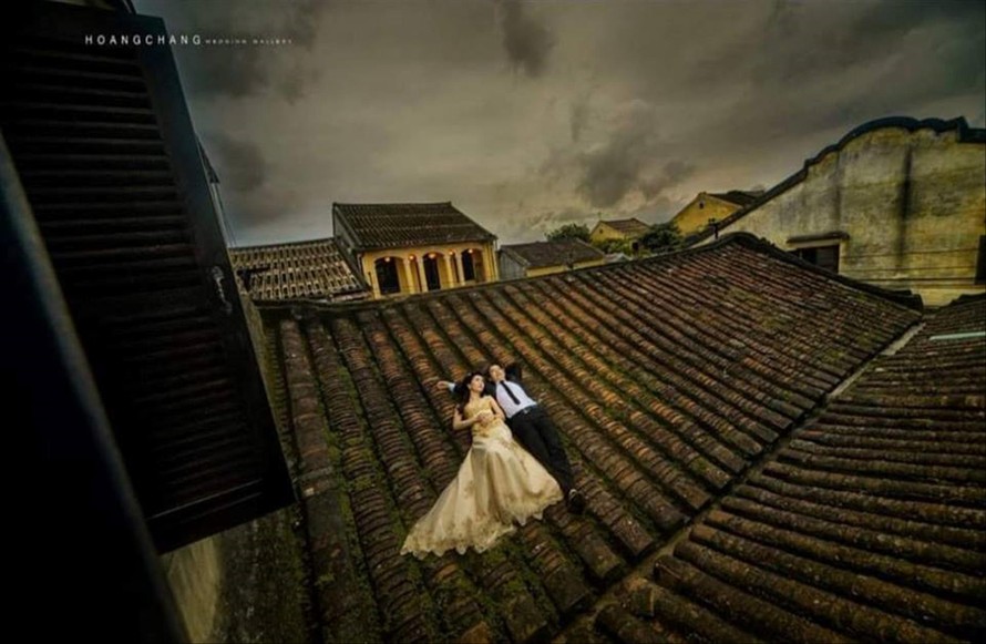 Một cặp đôi trèo lên mái ngói nhà cổ chụp ảnh cưới. Ảnh: FB 