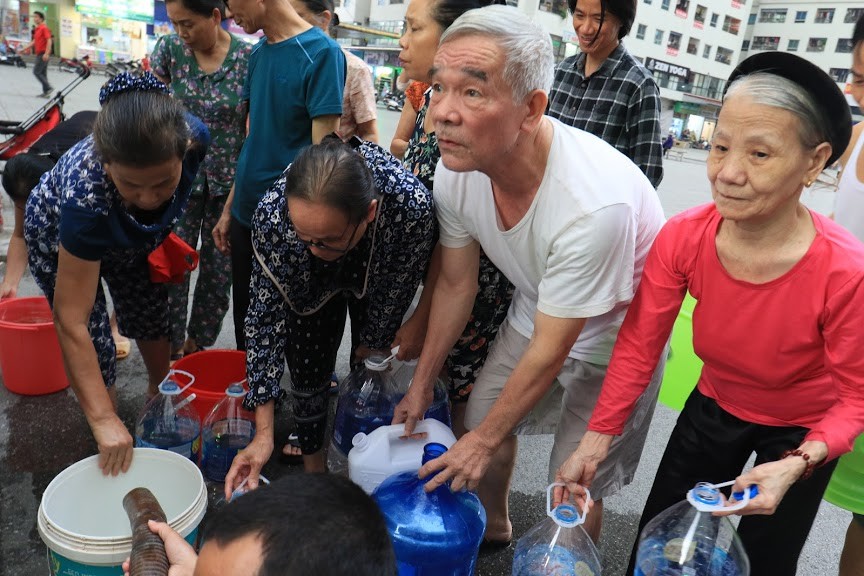 Các cụ già mang can đựng nước xếp hàng lấy từ xe téc chở đến khu Linh Đàm như thời bao cấp. Ảnh chụp 16h30 ngày 16/10. Ảnh: Như ý