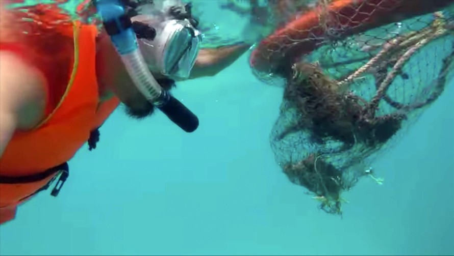 Anh Cao Mạnh Tuấn lặn biển vớt rác cứu các rặng san hô. (Ảnh chụp từ clip)