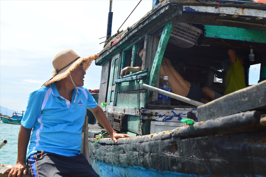 Lão ngư Nguyễn Quang tranh thủ vừa thả lưới, vừa tuyên truyền cho các ngư dân trên các tàu đánh bắt gần bờ. Ảnh: Giang Thanh 