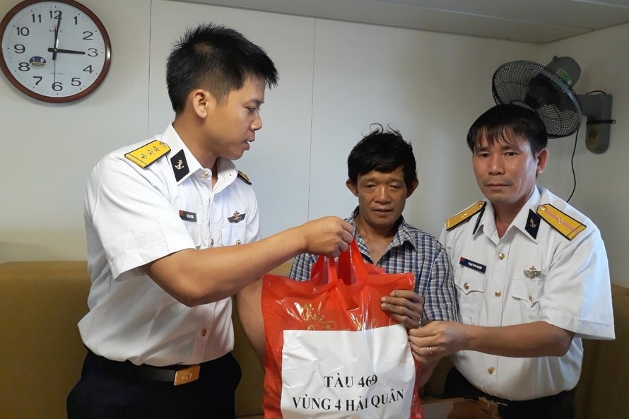 Thuyền trưởng Lê Văn Chung (bên trái) động viên, trao quà cho ngư dân tàu cá bị nạn, năm 2018