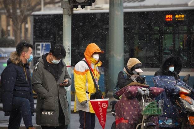 Người dân đeo khẩu trang chờ xe tại một ngã tư trong một buổi sáng tuyết rơi ở Bắc Kinh, ngày 19/1. Ảnh: AP 