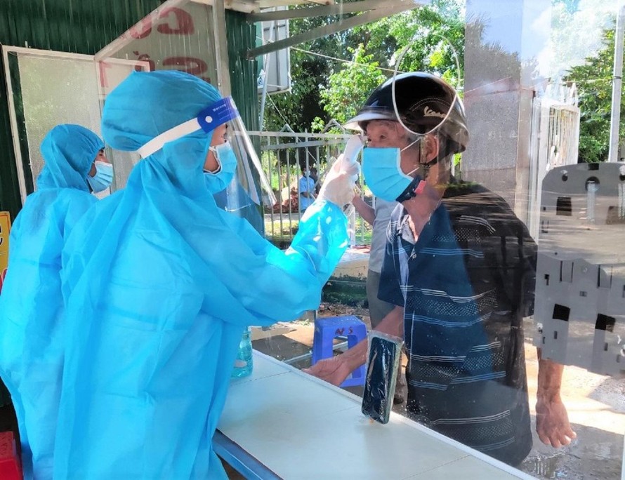 Tình nguyện viên hỗ trợ đo thân nhiệt cho người dân tại Trung tâm Y tế huyện Cư Jút