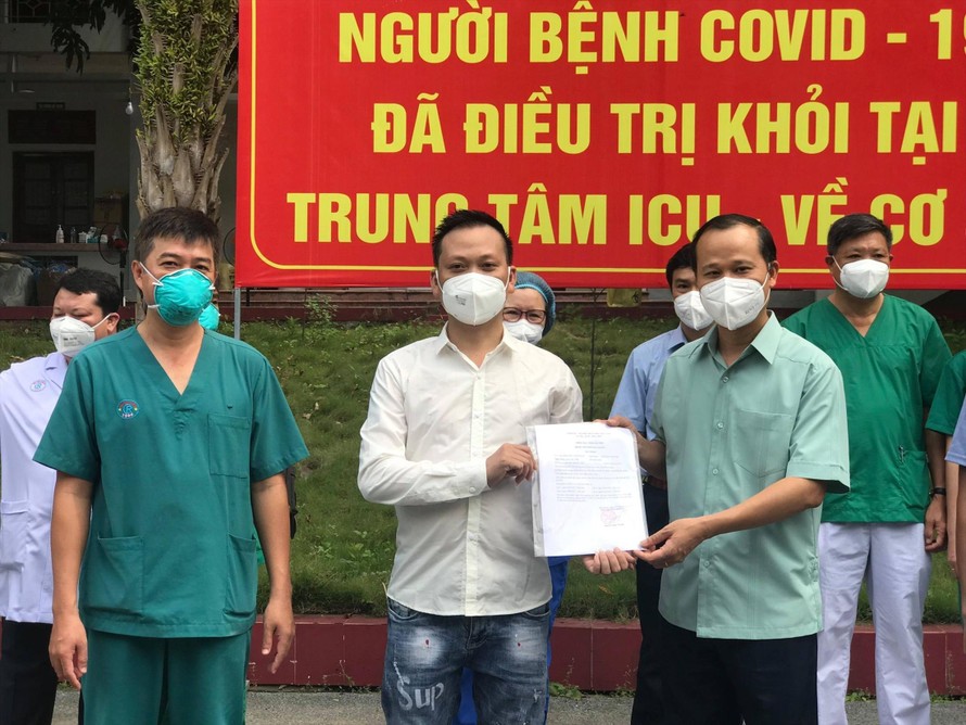 Anh N.V.G. (giữa) nhận giấy chứng nhận khỏi bệnh từ ông Mai Sơn, Phó Chủ tịch tỉnh Bắc Giang. Ảnh: N.Mai