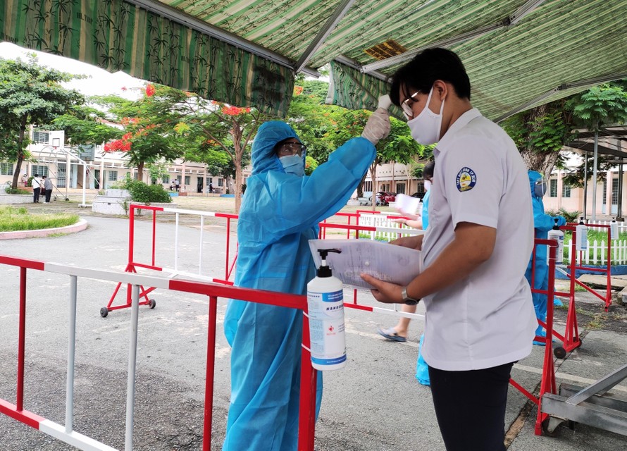 Trước buổi thi, thí sinh tại điểm thi Trường THCS Lê Quý Ðôn, TPHCM được kiểm tra thân nhiệt và yêu cầu khai báo y tế, trình giấy chứng nhận xét nghiệm âm tính. Ảnh: NGÔ TÙNG