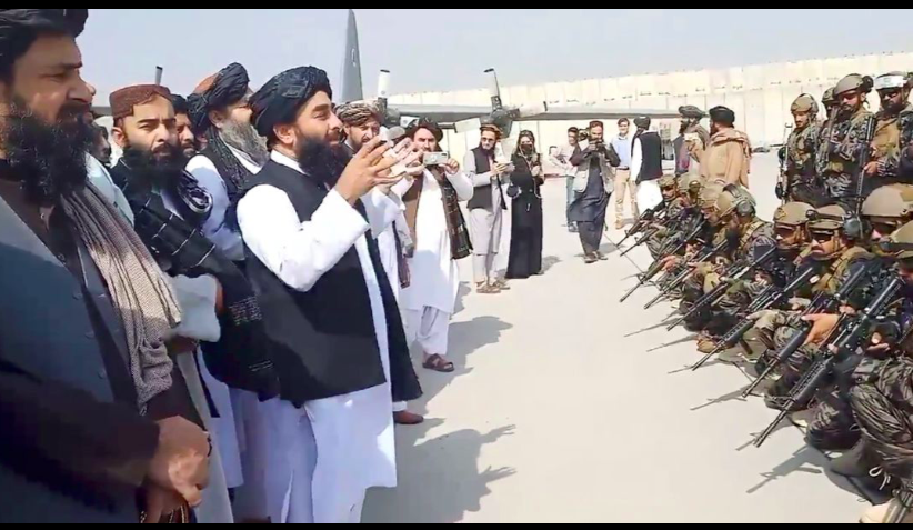 Phát ngôn viên Taliban Zabihullah phát biểu trước một nhóm tay súng tại sân bay Kabul ngày 31/8 Ảnh: Al Jazeera 